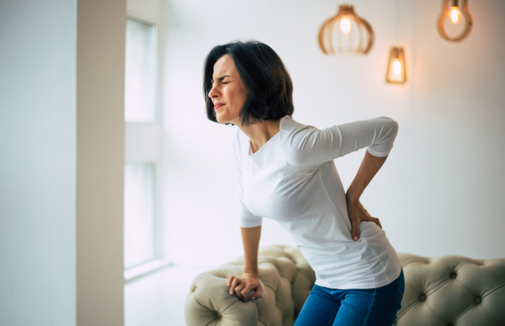 Jovem está segurando a parte inferior das costas enquanto sofre de fortes dores nas costas.