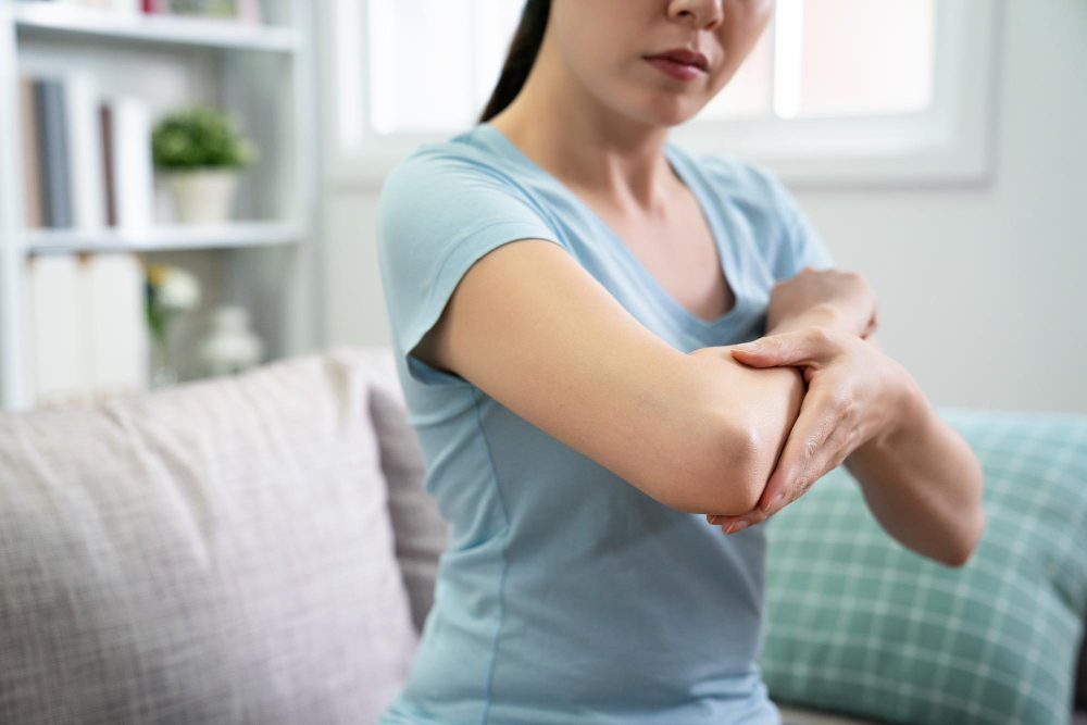 mulher olhando para seu braço direito com dor.