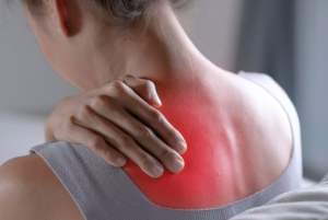 Mulher segurando ombro dolorido com outra mão, sintoma de fibromialgia.